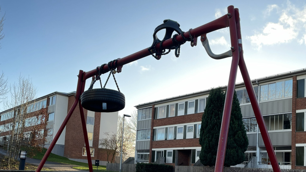 Två svarta gungor uppsnurrade på röd gungställning