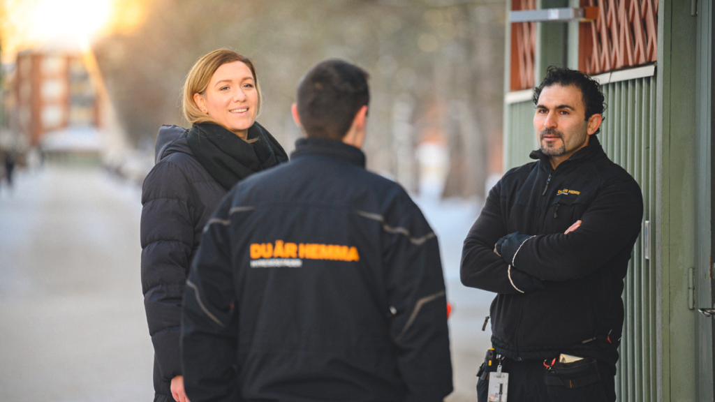 Tre anställda på Hyresbostäder står utomhus och konverserar.