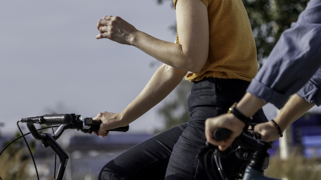 Två personer som cyklar jämsides sett i profil. 