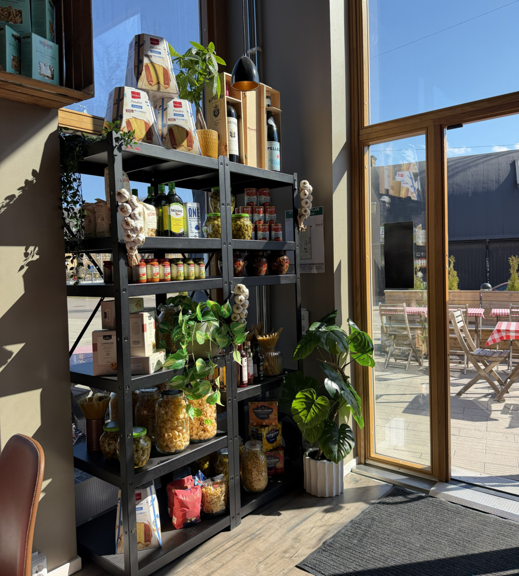 Hylla inne på en restaurang. Pasta, såser, vitlöksflätor och andra livsmedel på hyllorna. 