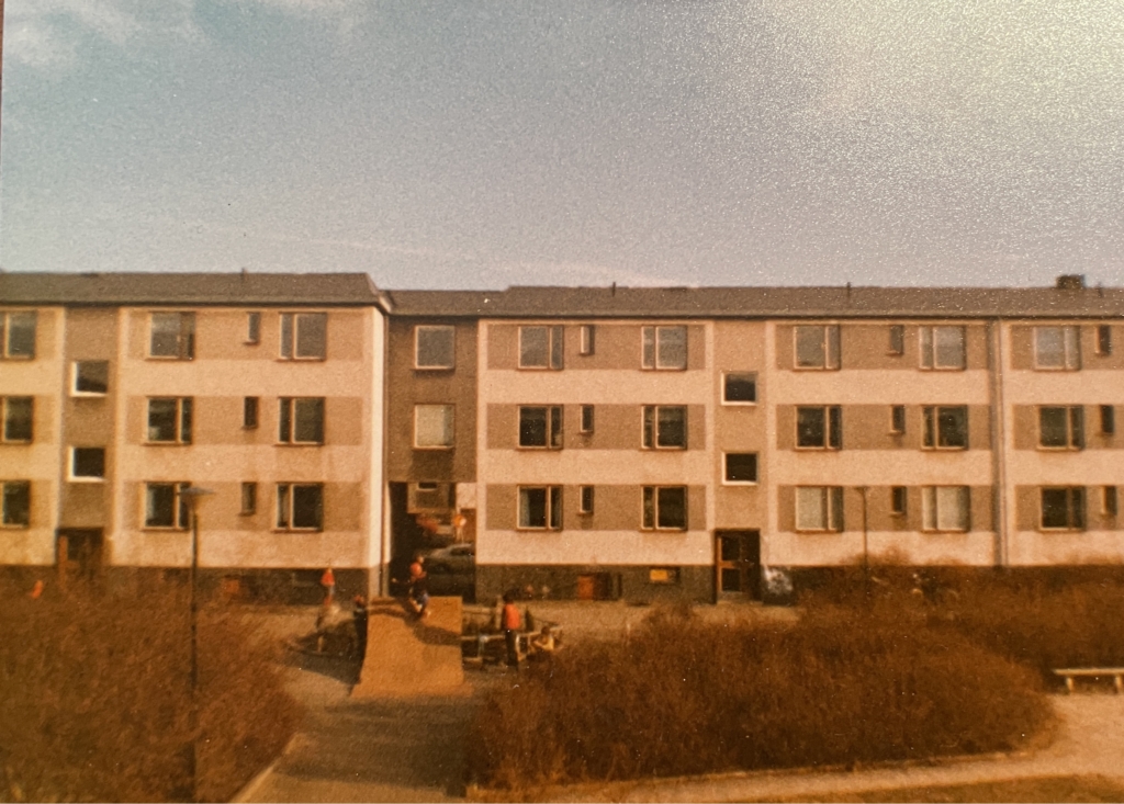 Gammeldags bild på lägenhetskomplex i Hageby, Norrköping. Lekande barn i förgrunden