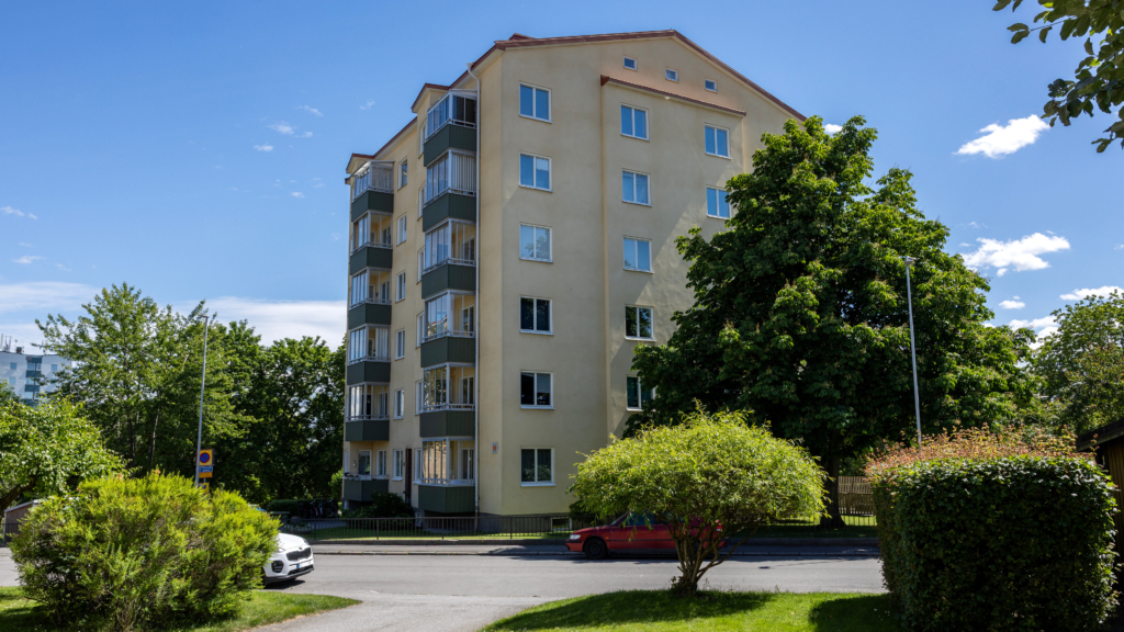 Ett flerbostadshus med en bil parkerad framför.