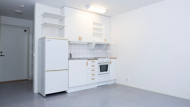 Interiörbild i en av lägenheterna på Konstantinopel. På bilden syns ett kök och ett rum med vita väggar och ljusgrått golv.