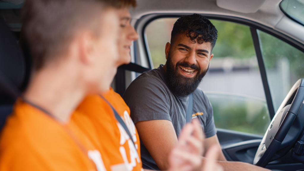 Handledare som sitter i en bil tillsammans med två juniorer.
